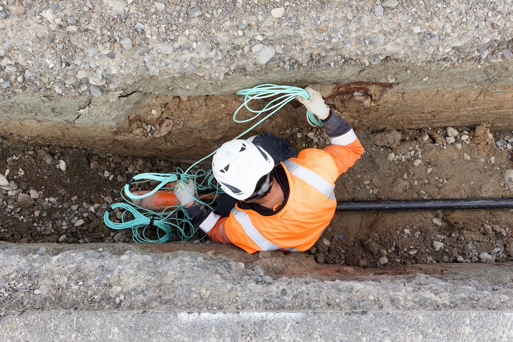 Aerial view of a contractor in a trench laying an electricity cable.